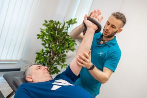Physiotherapeut führt gezielte Mobilisationsübung am Arm eines Patienten durch, individuelle Behandlung, Balance Aschaffenburg